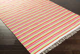 Close-up of Ahsahka Area Rug. Stripes of grass green, ivory, mauve, orange, and pink with fringe on dark wood floor. Corner