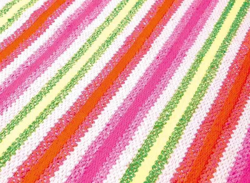Close-up of the hand woven Ahsahka Area Rug with grass green, ivory, pink, and orange stripes. Styleshot