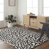 Living room scene with Akeem Leopard Print Area Rug in beige and dark gray, styled with a wood cabinet and black chair. Roomscene-Rectangle