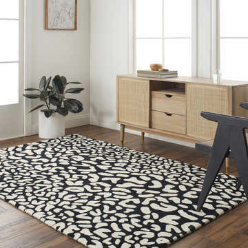 Living room scene with Akeem Leopard Print Area Rug in beige and dark gray, styled with a wood cabinet and black chair. Roomscene-Rectangle