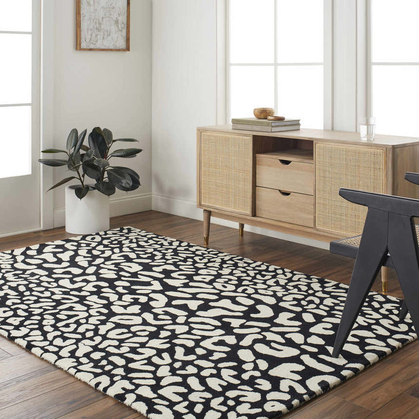 Living room scene with Akeem Leopard Print Area Rug in beige and dark gray, styled with a wood cabinet and black chair. Roomscene-Rectangle