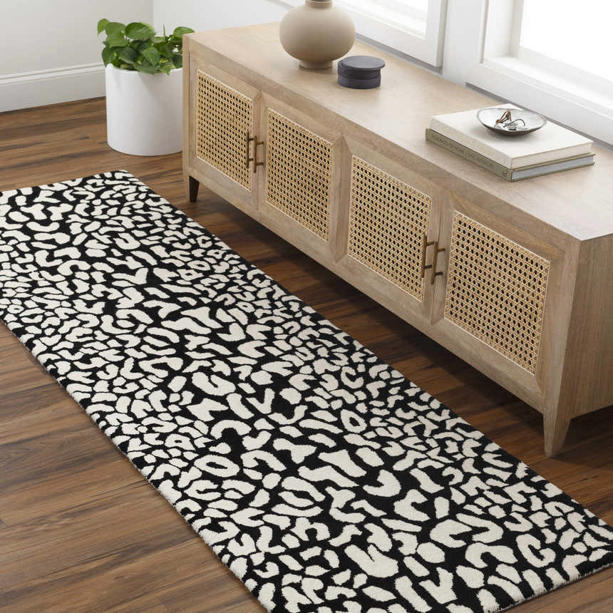Hallway scene with Akeem Leopard Print Area Rug. Beige cabinet, wood floors, and a black and white rug. Roomscene-Runner