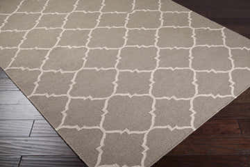 Close-up of the Akron Area Rug, a hand-woven wool rug with a brown and taupe geometric trellis pattern. Corner