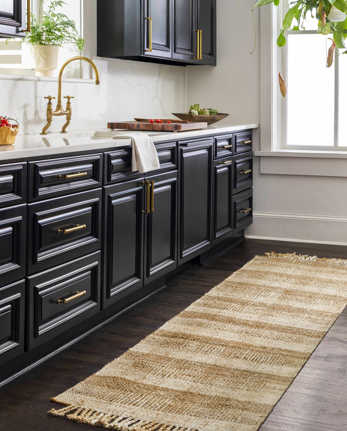 Farmhouse kitchen with black cabinets and a natural Alara Area Rug runner on dark wood floors. Roomscene-Runner