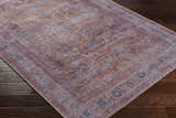 Close-up of the Alcoy Washable Area Rug. Features a traditional, oriental design in dark purple, brown, and pale pink tones. Corner