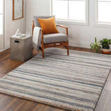Living room scene with striped Alejo Area Rug, gray chair, and wood floors. Modern, inviting space. Roomscene-Rectangle