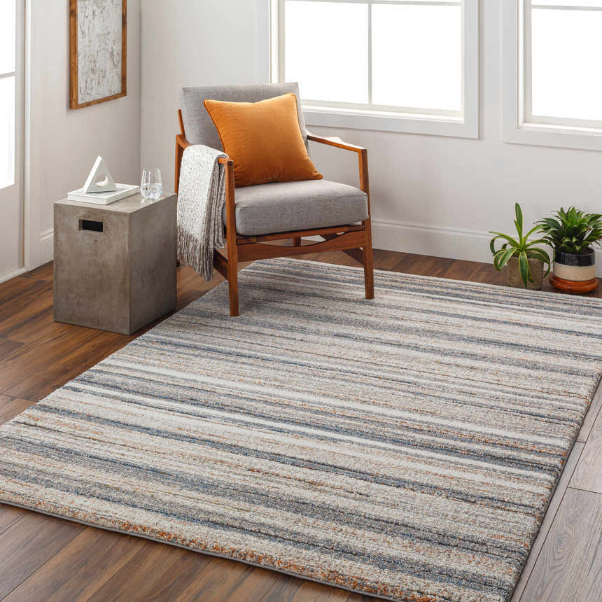 Living room scene with striped Alejo Area Rug, gray chair, and wood floors. Modern, inviting space. Roomscene-Rectangle