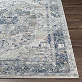 Close-up of the Allerton Area Rug showing its beige, charcoal, dark blue, and gray traditional pattern on dark wood floors. Front
