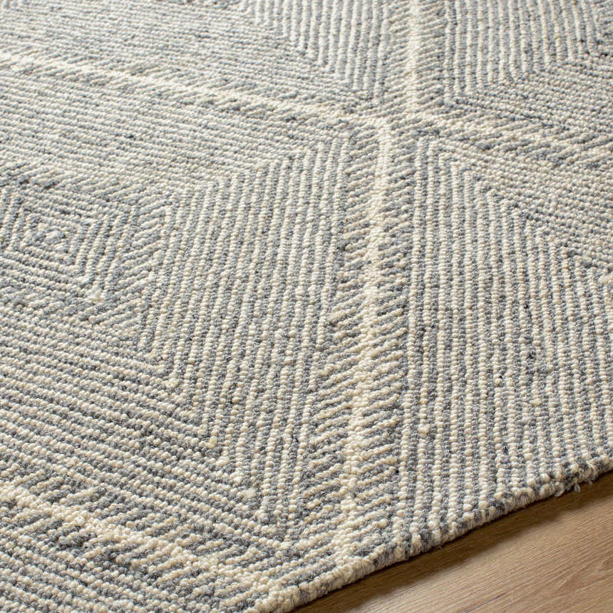 Close up of the hand tufted Amari Area Rug showing light and natural gray geometric pattern and wool texture. Texture