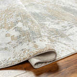Close-up of the Ambra Thick Luxe Boutique Rug showing its gray, brown, and white contemporary pattern and plush texture. Fold