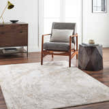 Living room scene with Ambra Thick Luxe Boutique Rug in cloud gray and brown tones, styled with a gray chair and wood furniture. Roomscene-Rectangle