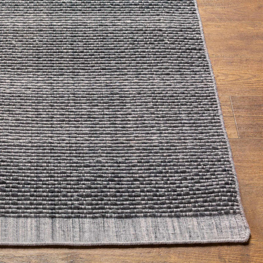 Close-up of the Yong Hand Loomed Gray Indoor Outdoor Rug showing its charcoal, gray, and light slate woven texture. Front