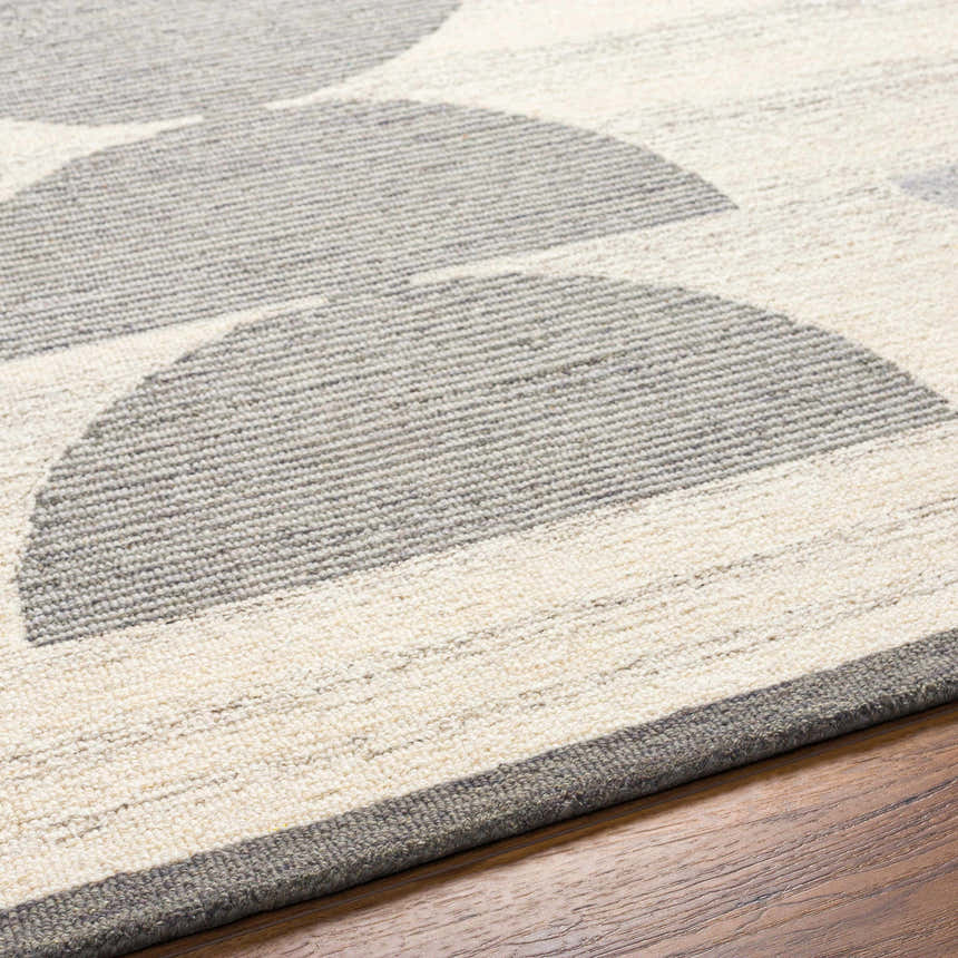 Close up of the Anahi Area Rug showing its beige and gray geometric pattern and hand tufted wool texture. Texture