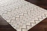 Close-up of the hand woven Whittington Gray&Cream Wool Rug showing its geometric pattern and textured wool on wood floor. Corner