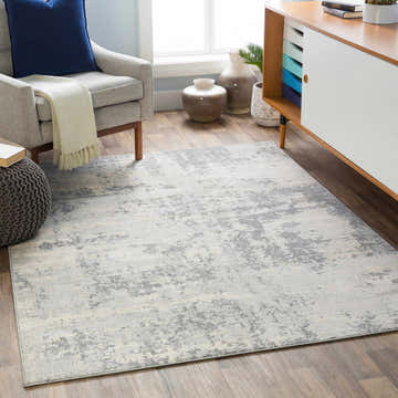 Living room scene with a gray Apison Area Rug, armchair, and modern cabinet. Gray, ivory, and silver tones. Roomscene-Rectangle