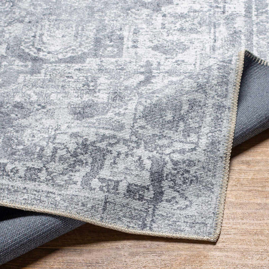 Close-up of the gray Aquino Washable Area Rug showing the traditional oriental pattern and durable machine-woven construction. Fold