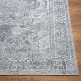 Close-up of the gray Aquino Washable Area Rug showing its traditional oriental pattern and soft texture on a wood floor. Front