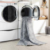 Laundry room scene with Aquino Washable Area Rug in charcoal and gray coming out of the dryer. Washing-Machine