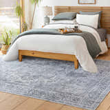 Bedroom scene with a gray Aquino Washable Area Rug, wood floors, and a modern bed with gray and white bedding. Roomscene-Rectangle