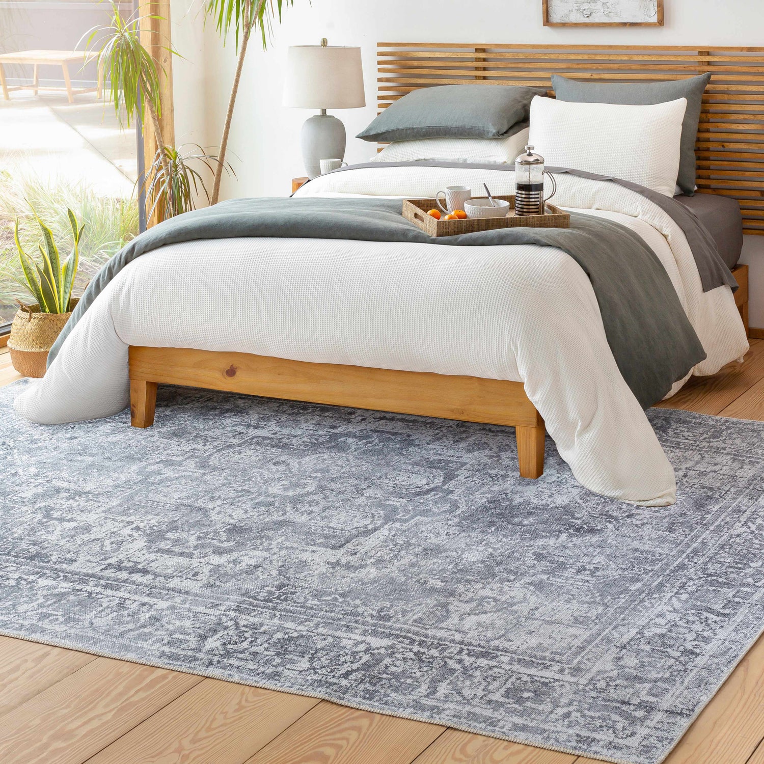 Bedroom scene with a gray Aquino Washable Area Rug, wood floors, and a modern bed with gray and white bedding. Roomscene-Rectangle