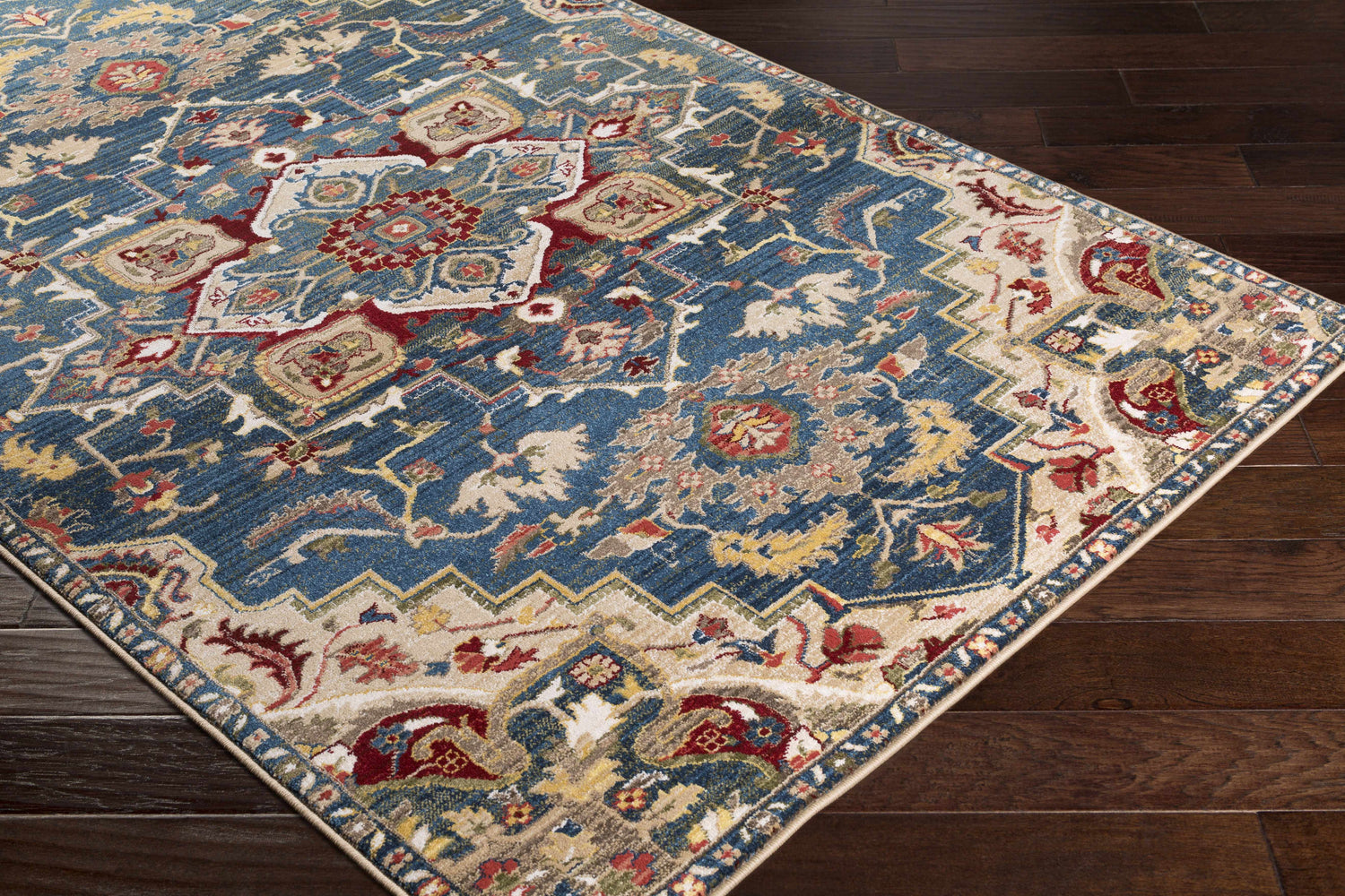 Close-up of the Argyle Area Rug, a machine-woven rug with a traditional design in brick red, navy, and tan colors. Corner