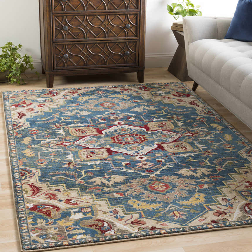 Living room scene with Argyle Area Rug in blue, red, and tan, styled with wood dresser and gray sofa. Bohemian style. Roomscene-Rectangle