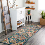 Bathroom scene with Argyle Area Rug runner in blue, red, and beige. White vanity, wood ladder, and plants create a cozy, stylish space. Roomscene-Runner