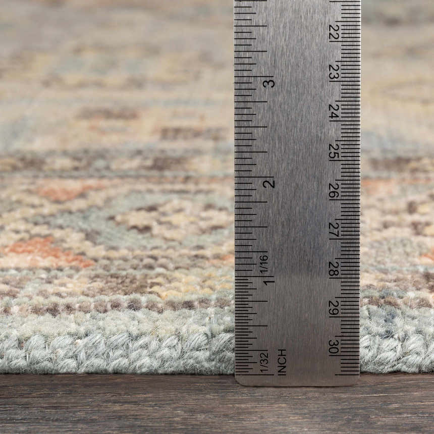 Close up of Aripeka Area Rug showing texture, pile height, and colors: beige, blue, camel, and sage. Hand knotted wool rug. Pile
