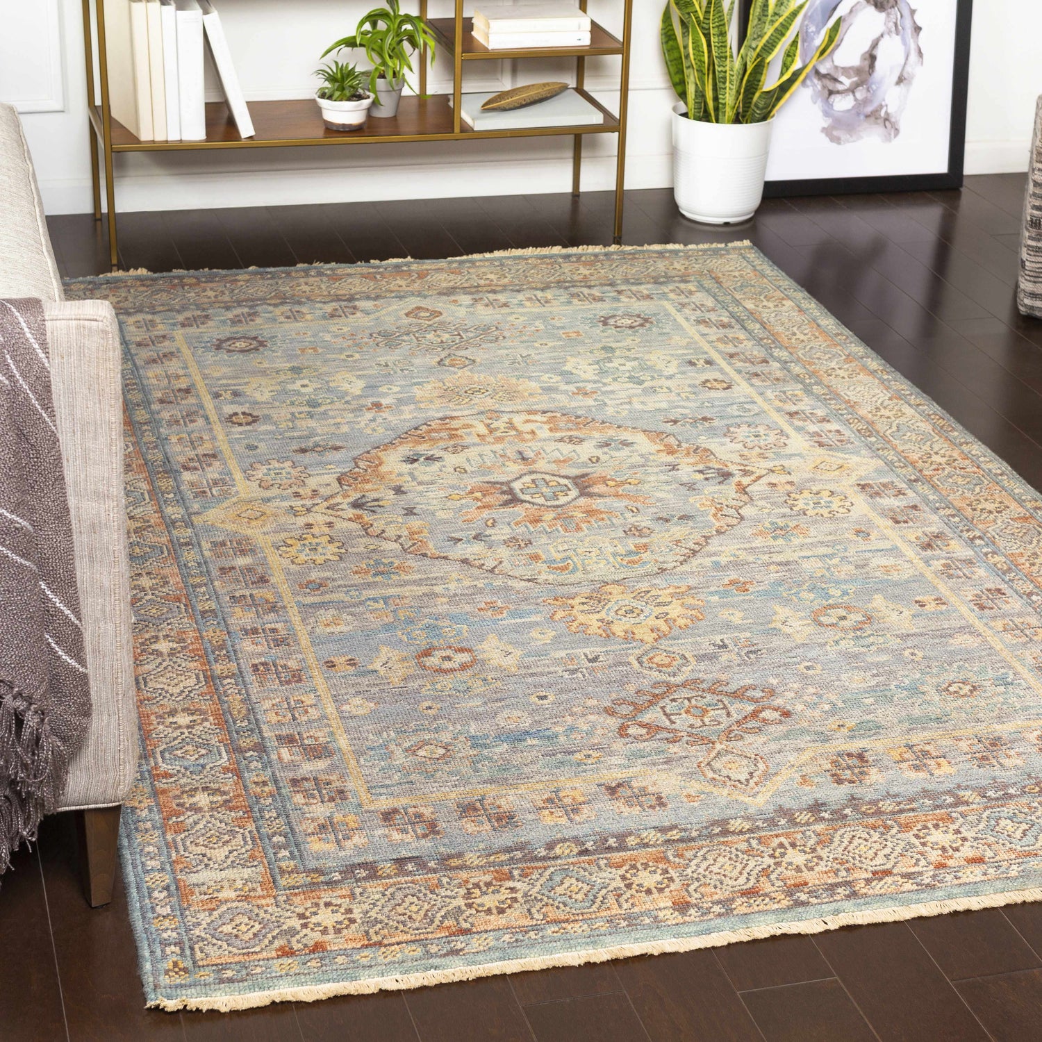 Living room scene with Aripeka Area Rug. Beige sofa, dark wood floors, blue, tan, and beige vintage style rug. Roomscene-Rectangle