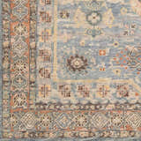 Close up of the hand-knotted Aripeka Area Rug with a traditional blue, beige, and tan oriental pattern. Swatch