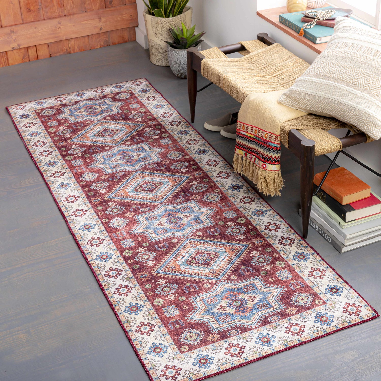 Entryway scene with Armadale Clearance Rug runner in red, blue, and beige. Bohemian style with bench, plants, and gray wood floor. Roomscene-Runner