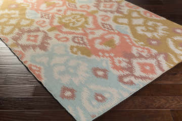 Close-up of the Aspinwall Area Rug. Hand-woven wool rug with dusty coral, light gray, mustard, and pale blue ikat pattern. Corner