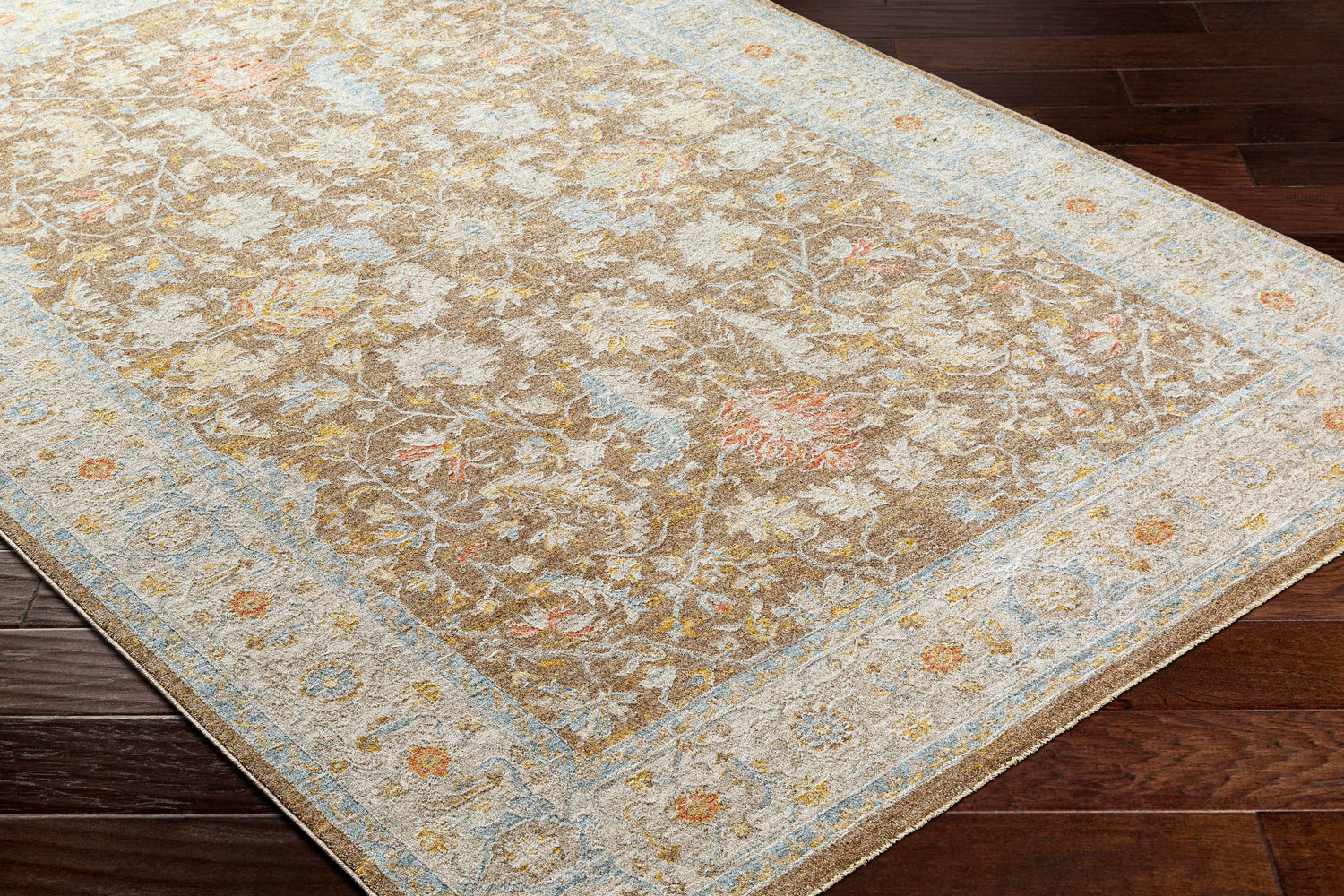 Close-up of Atli Thick Luxe Area Rug in amber, brown, pink, gray and taupe on dark wood floor. Floral, traditional pattern. Corner