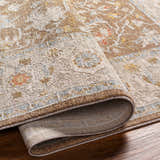 Close-up of the Atli Thick Luxe Area Rug showing its amber, brown, and dusty pink traditional floral pattern and thick, soft texture. Fold
