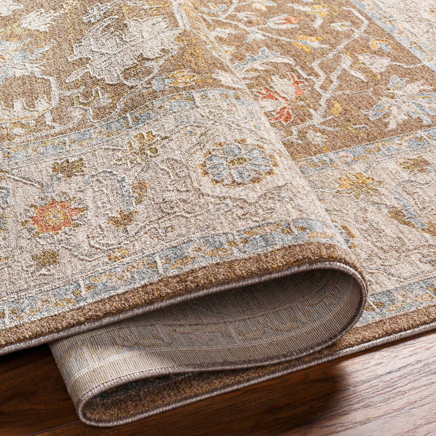Close-up of the Atli Thick Luxe Area Rug showing its amber, brown, and dusty pink traditional floral pattern and thick, soft texture. Fold