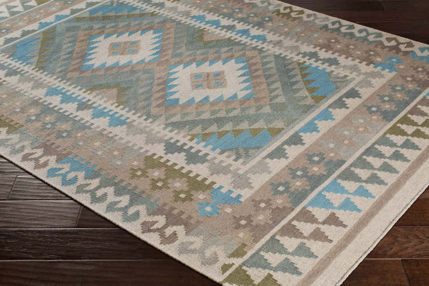 Close-up of the hand woven Auchterarder Carpet. Farmhouse style rug with aqua, blue, sage, and brown geometric pattern. Corner