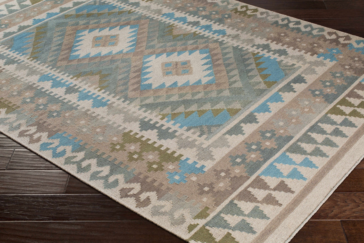 Close-up of the hand woven Auchterarder Carpet. Farmhouse style rug with aqua, blue, sage, and brown geometric pattern. Corner