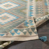 Close-up of the hand woven Auchterarder Carpet. Farmhouse style rug in aqua, blue, sage, and brown with geometric pattern and tassel. Fold