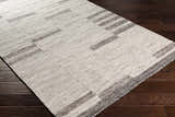Close-up of the Auchinleck Area Rug showing the cream and charcoal geometric pattern and hand-woven texture on dark wood floors. Corner