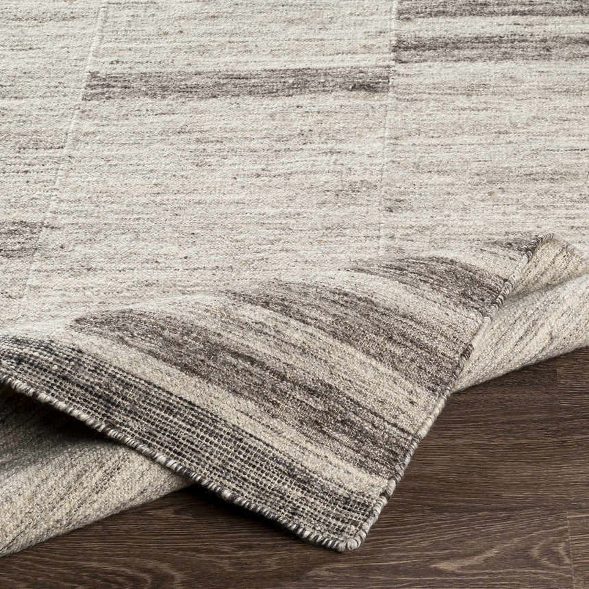 Close-up of the Auchinleck Area Rug showing its charcoal, cream, and gray horizontal stripes and hand-woven texture. Fold