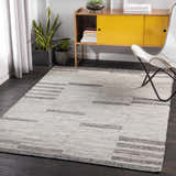 Living room scene with a charcoal and cream Auchinleck Area Rug, yellow cabinet, white chair, and dark wood floors. Roomscene-Rectangle
