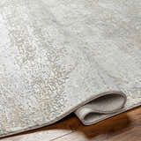 Close-up of the Avani Thick Luxe Boutique Rug showing its gray, nutmeg, and white textured design and machine-woven construction. Fold