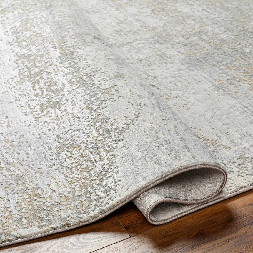 Close-up of the Avani Thick Luxe Boutique Rug showing its gray, nutmeg, and white textured design and machine-woven construction. Fold