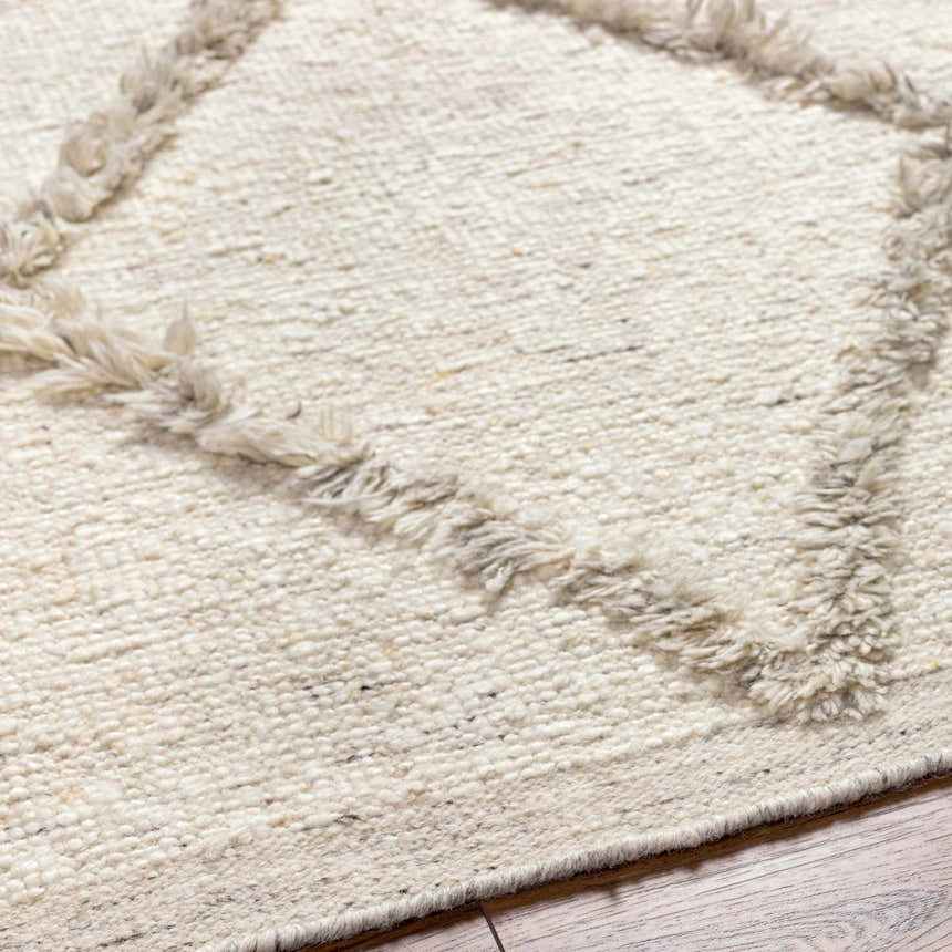 Close-up of the Awen Hand Knotted Wool Area Rug, showing beige wool texture and geometric charcoal pattern. Texture