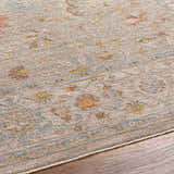 Close-up of the Awena Thick Luxe Area Rug. Traditional floral pattern in amber, dusty pink, and light olive on a taupe background. Texture