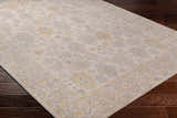 Close-up of the Ayele Thick Luxe Statement Rug in charcoal, gray, mustard, and tan on dark wood flooring. Corner