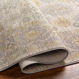 Close-up of the Ayele Thick Luxe Statement Rug showing its charcoal, mustard, and gray traditional pattern and plush texture. Fold