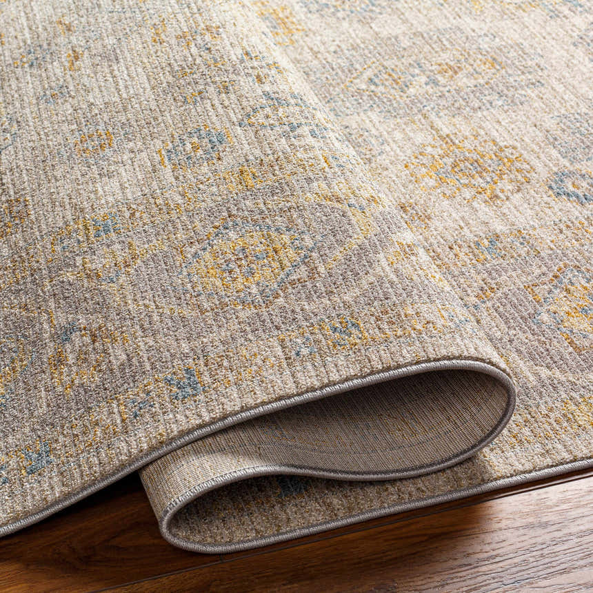 Close-up of the Ayele Thick Luxe Statement Rug showing its charcoal, mustard, and gray traditional pattern and plush texture. Fold