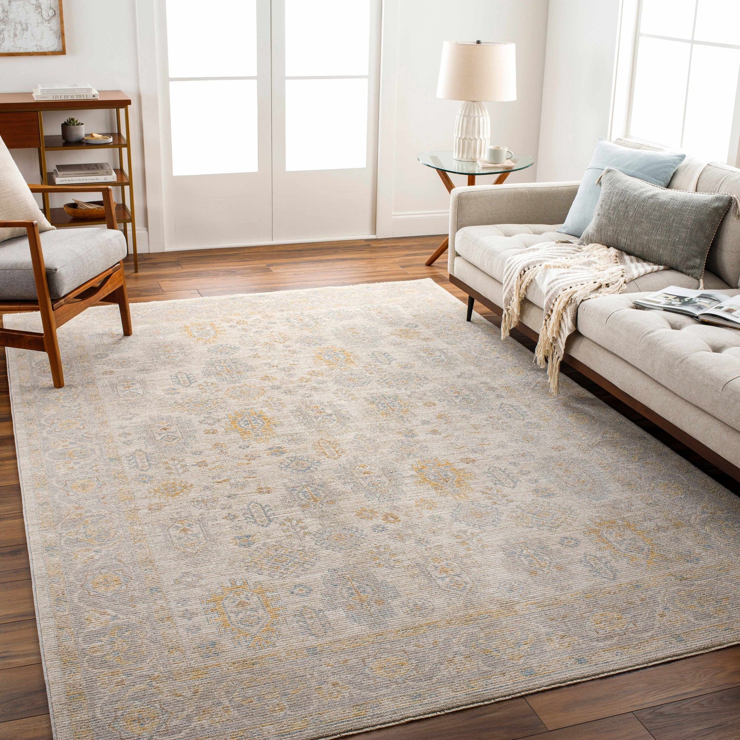 Living room scene with a neutral sofa and the Ayele Thick Luxe Statement Rug in charcoal, gray, mustard, and tan. Roomscene-Rectangle