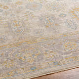 Close-up of the Ayele rug showing its traditional pattern in charcoal, mustard, and gray on a textured polyester weave. Texture